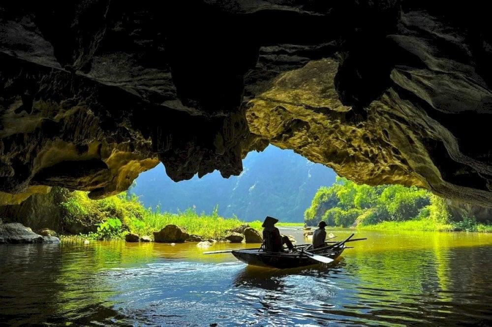 The boat ride through these caves is the perfect way to experience Tam Coc’s tranquil beauty, with towering limestone peaks and lush green fields surrounding the river